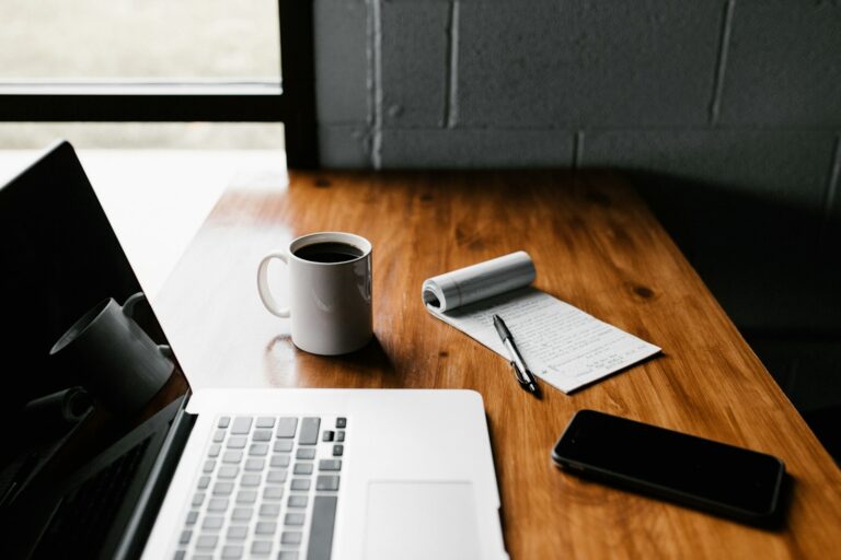 SEO vs. SEA: Laptop, Tasse und Smartphone auf einem Schreibtisch