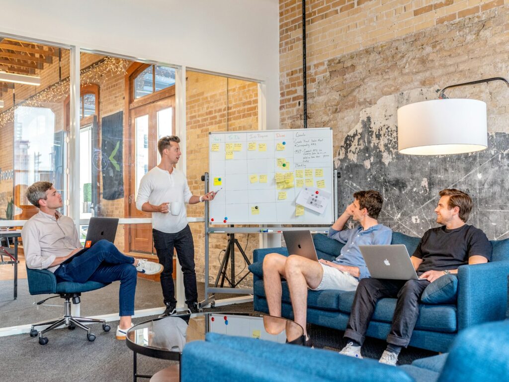 Digital-Marketing-Agentur erklärt Strategie am Whiteboard vor einem Team mit Laptops