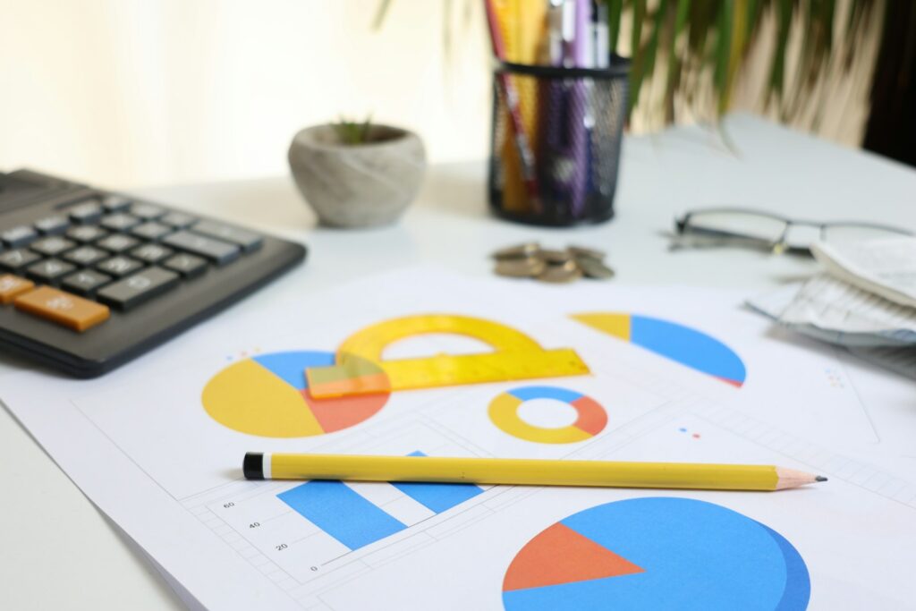 Google Ads Budget kontrollieren: Schreibtisch mit Taschenrechner, Diagrammen und Stift