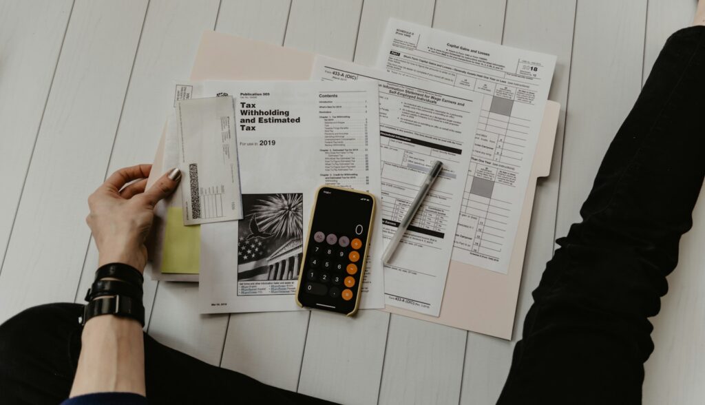 Google Ads Budget planen: Person mit Unterlagen, Stift und Taschenrechner
