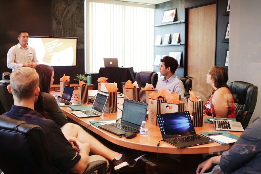 KI-SEO-Agentur im Meeting: Mann präsentiert vor einem Team mit Laptops