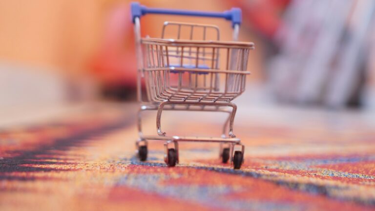 KI-Shopping: Kleiner Einkaufswagen auf einem Teppich als Symbol für den Onlinekauf