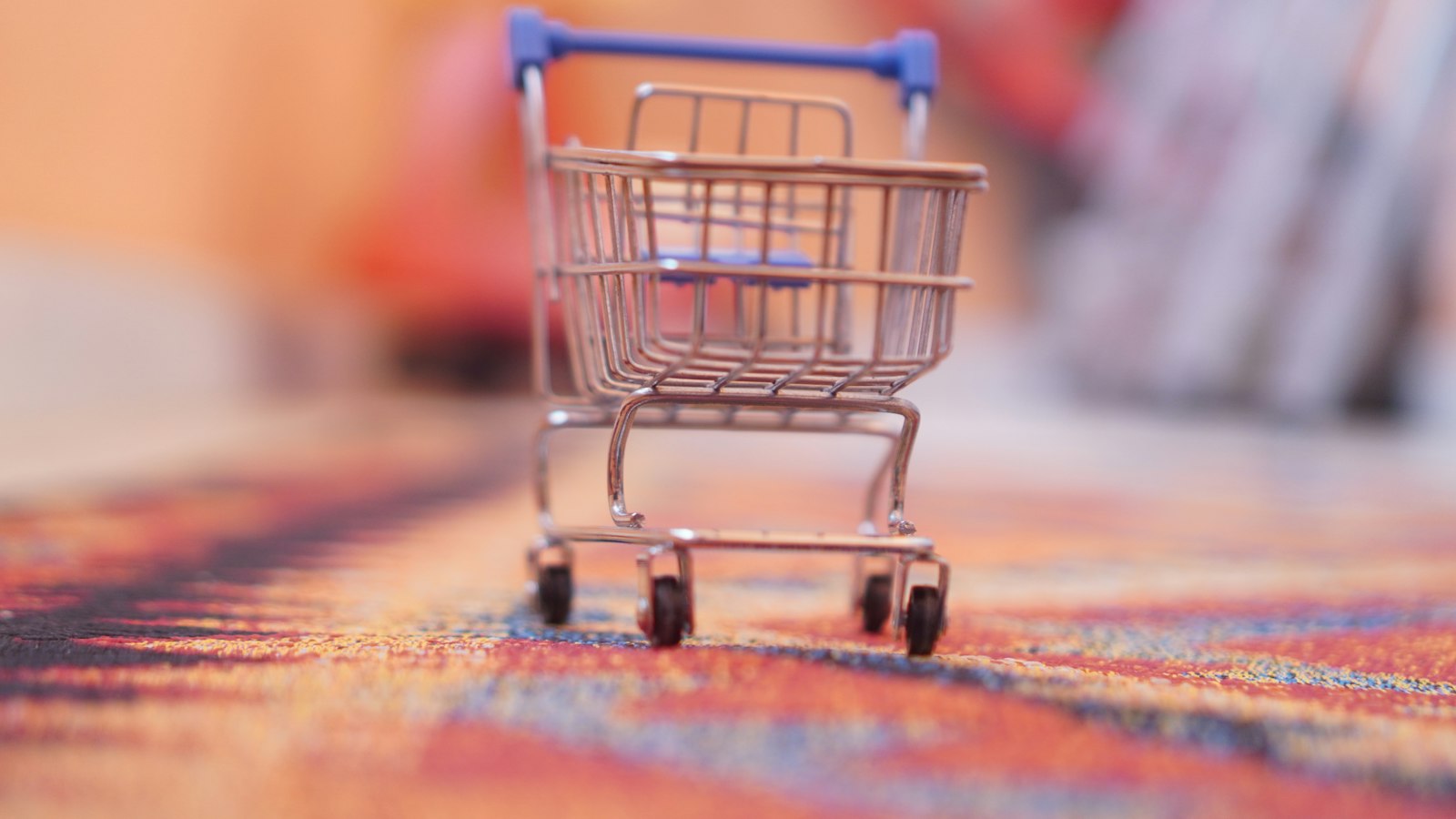 KI-Shopping: Kleiner Einkaufswagen auf einem Teppich als Symbol für den Onlinekauf