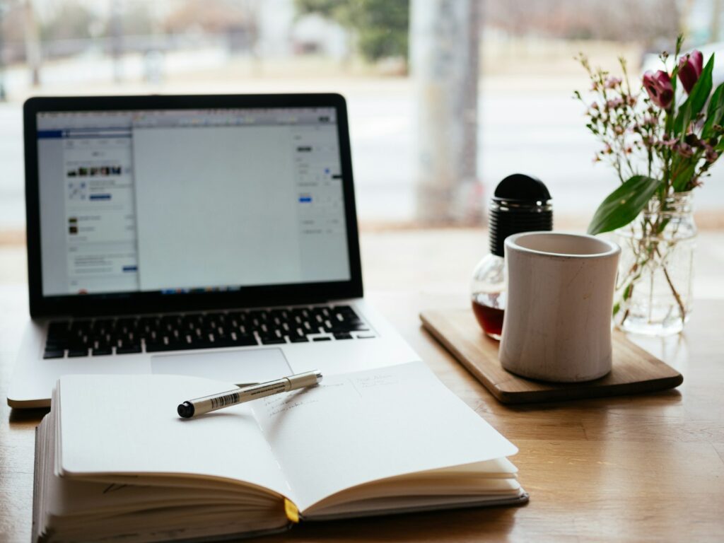 Länge von Blogartikeln planen: Laptop neben einem aufgeschlagenen Buch