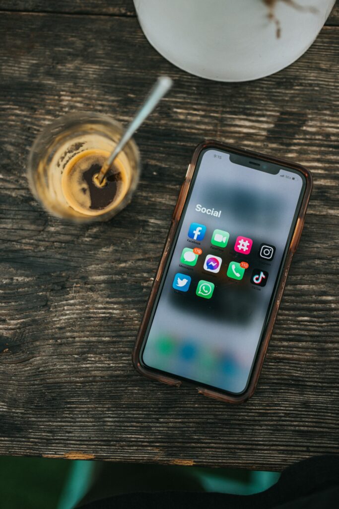 Social Media Marketing Kosten: Smartphone mit Social-Media-Apps neben einem Glas Kaffee