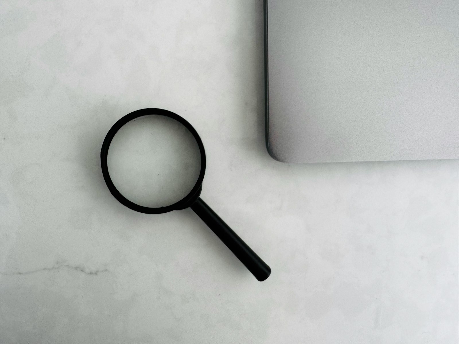 SEO Dienstleistungen: Lupe neben einem Laptop auf dem Schreibtisch