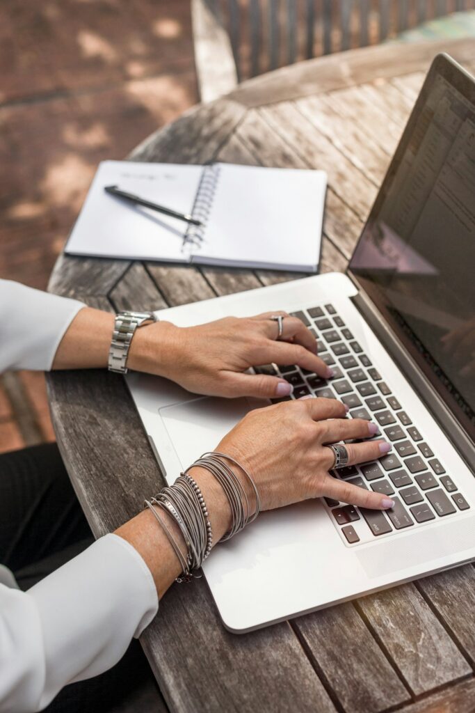 Ankertext formulieren: Person tippt auf einem Laptop an einem Holztisch