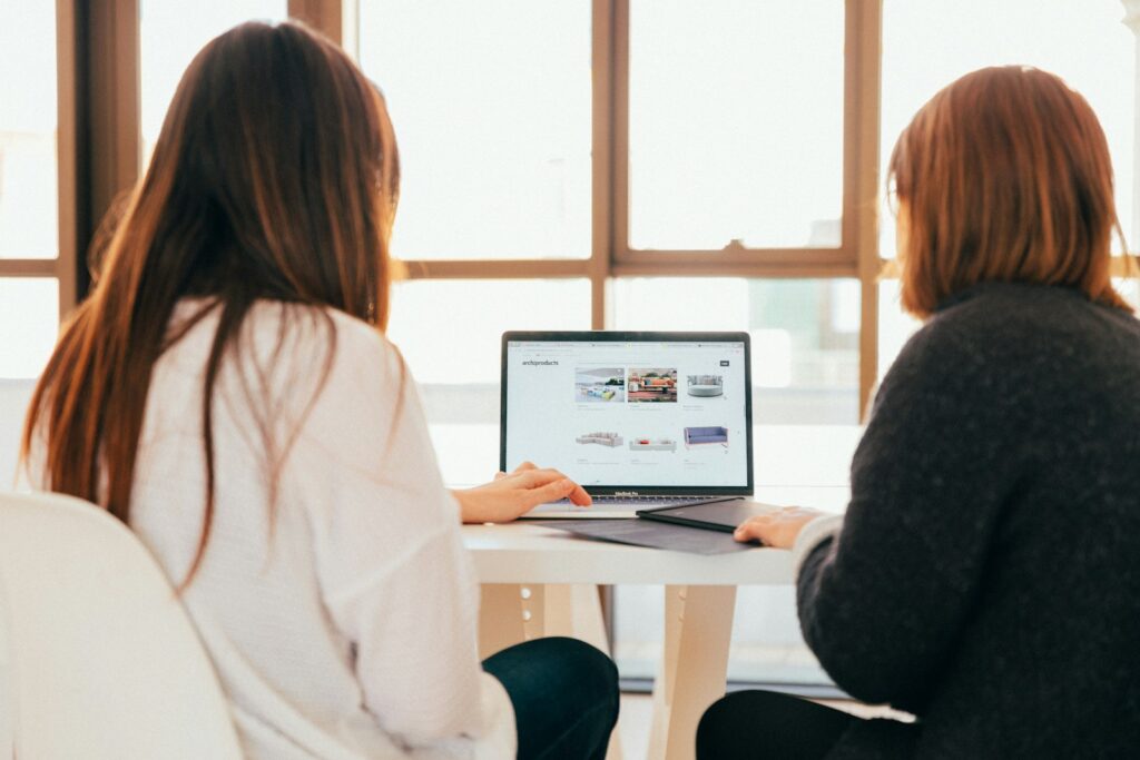 Zwei Kolleginnen besprechen Aufgaben eines Digital Marketing Specialist am Laptop