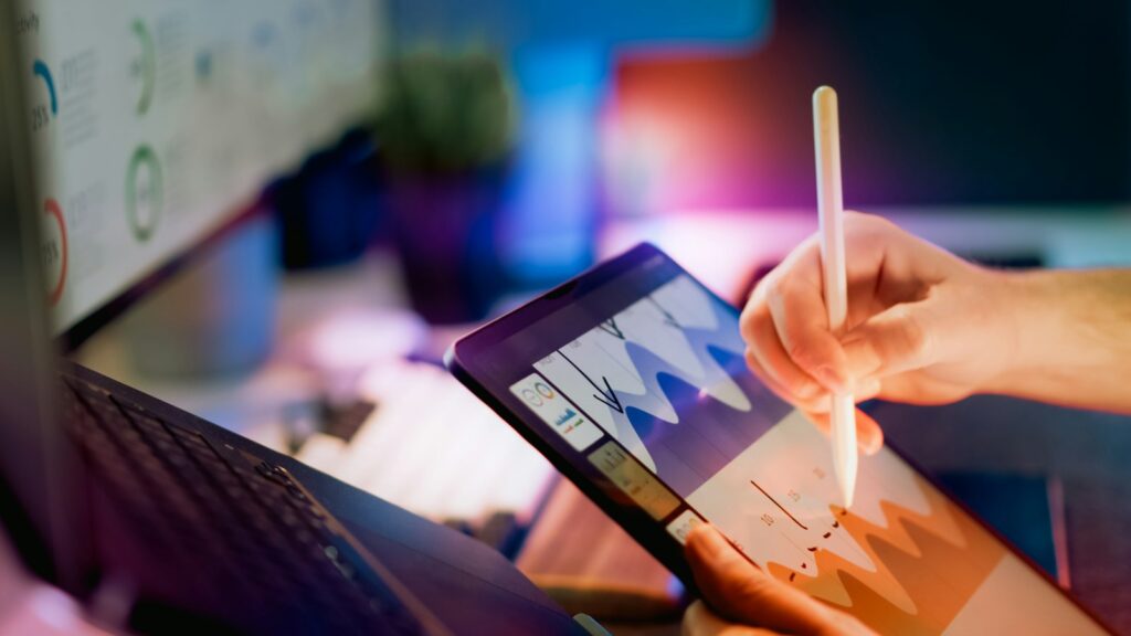Marketing-KPIs auswerten: Person arbeitet mit Stift an einem Tablet mit Diagrammen