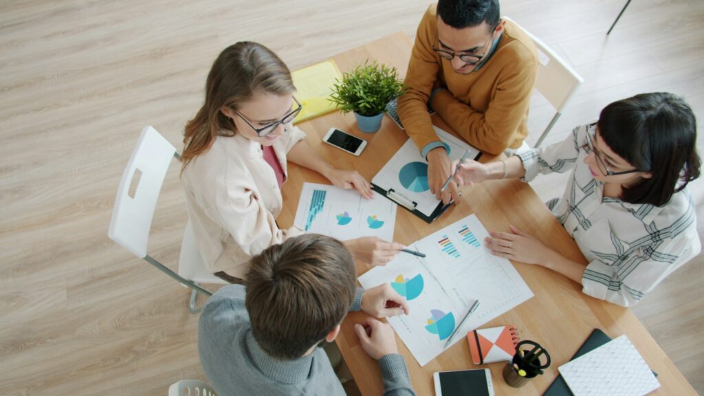 Marketing-KPIs im Team besprechen: Vier Personen arbeiten am Tisch mit Diagrammen