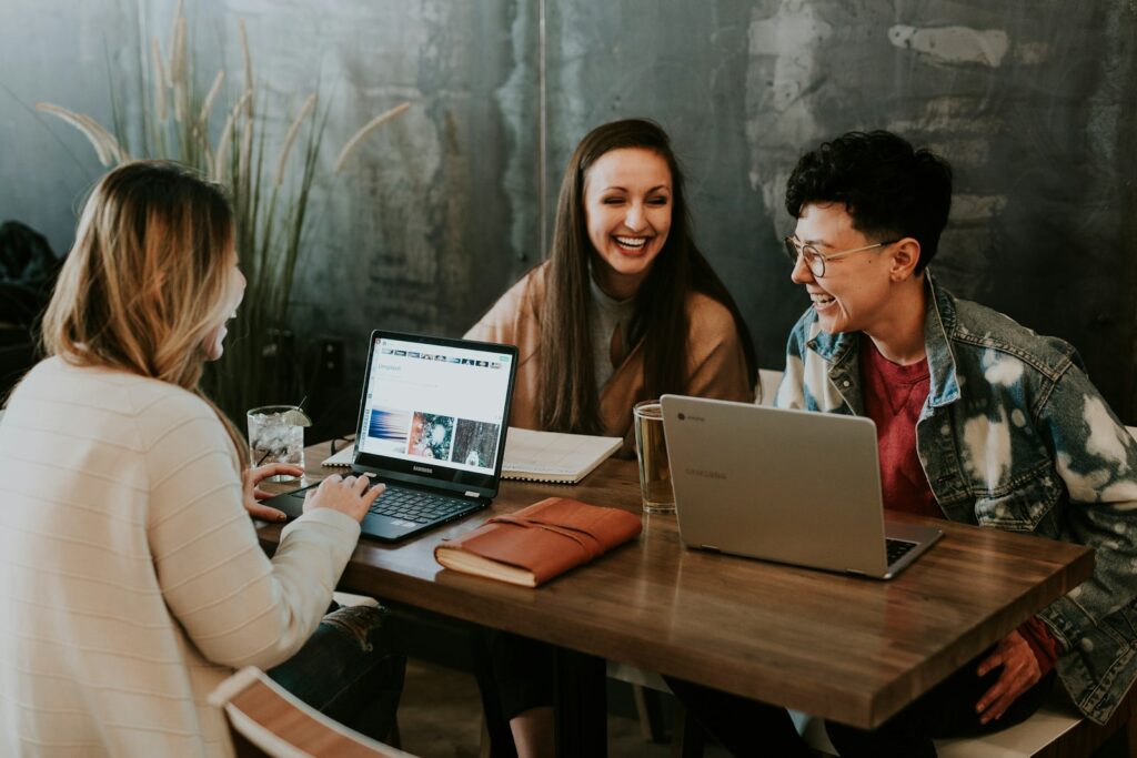 Reddit-Marketing lebt vom Austausch: Drei Menschen lachen gemeinsam an einem Tisch