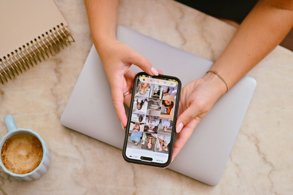 Reddit-Marketing: Person hält Smartphone mit Social-Media-Feed über einen Laptop