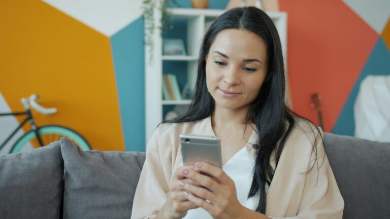 Meta Ads erreichen Nutzer am Smartphone: Frau schaut auf dem Sofa auf ihr Handy