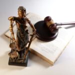 SEO für Anwälte: Justitia-Statue, Richterhammer und aufgeschlagenes Gesetzbuch