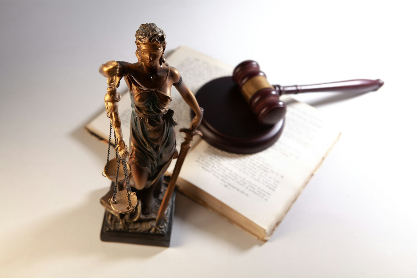 SEO für Anwälte: Justitia-Statue, Richterhammer und aufgeschlagenes Gesetzbuch